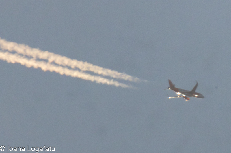 Plane soaring high with trails across the sky
